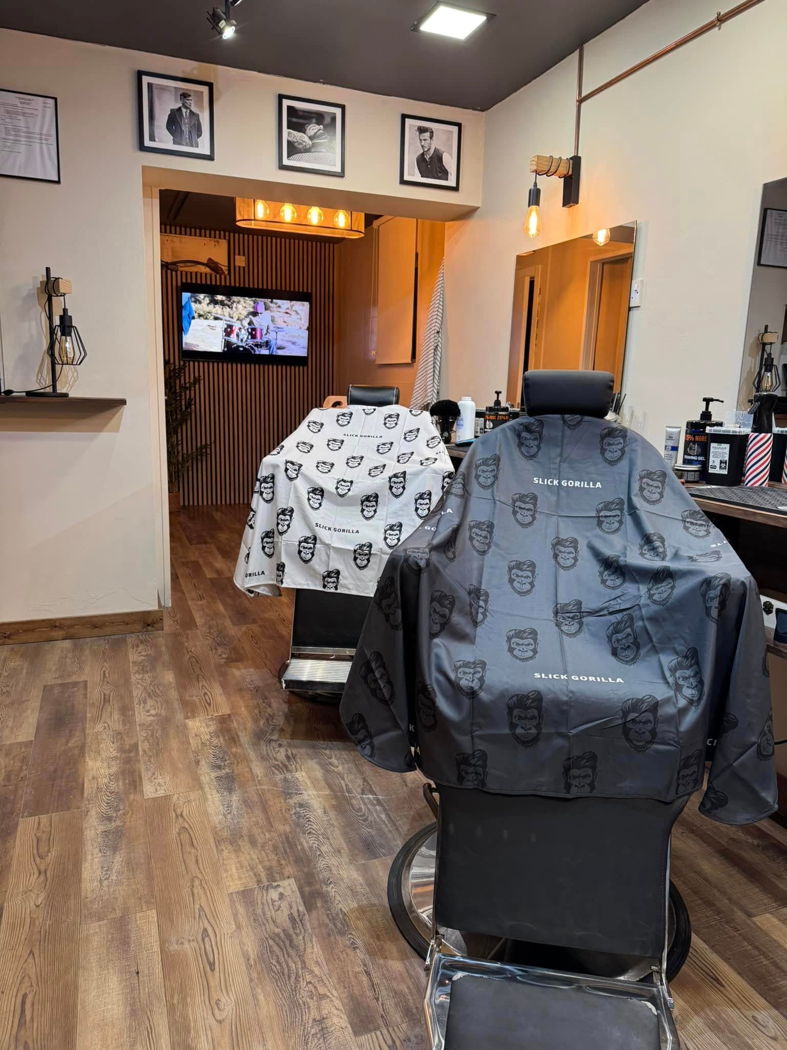 The shop floor at The Barbers Club, two barber chairs draped with patterned capes
