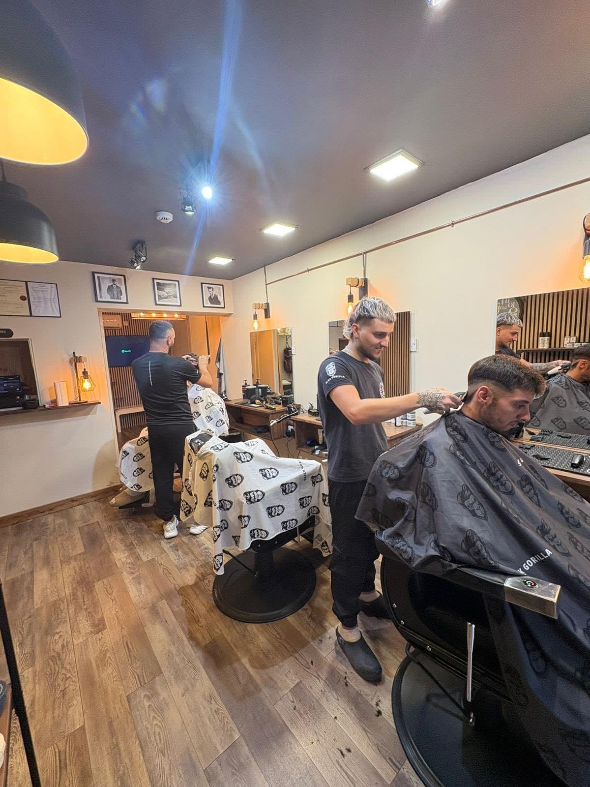 Two barbers working on clients across the shop floor